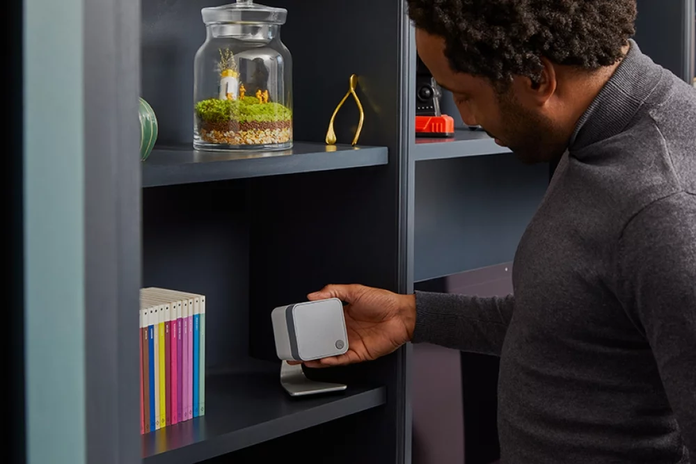 Man looking at white minx min 12 speaker on table stand in bookshelf
