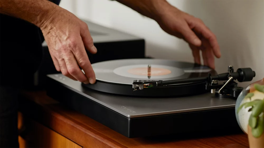 person lowering a record onto alva tt v2 turntable