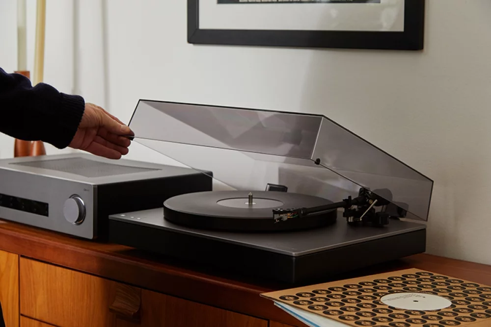 person lowering dust cover on alva tt v2 turntable