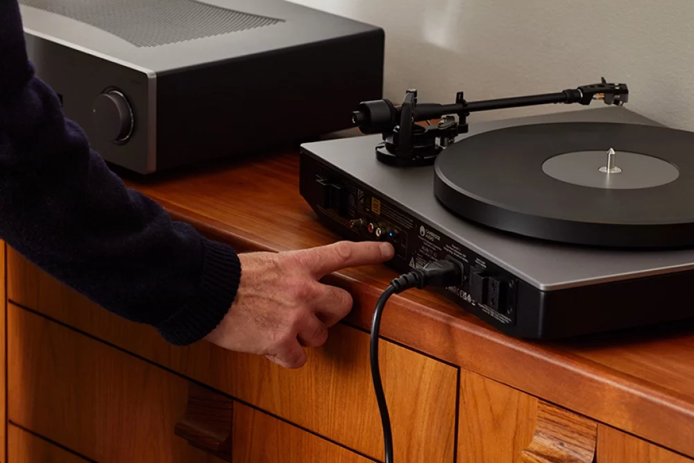 Person pressing button on back of alva tt v2 turntable