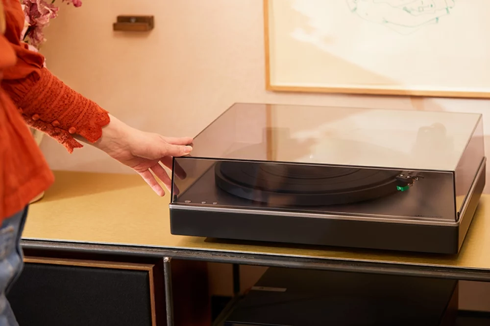 Woman lowering dust cover on alva st turntable